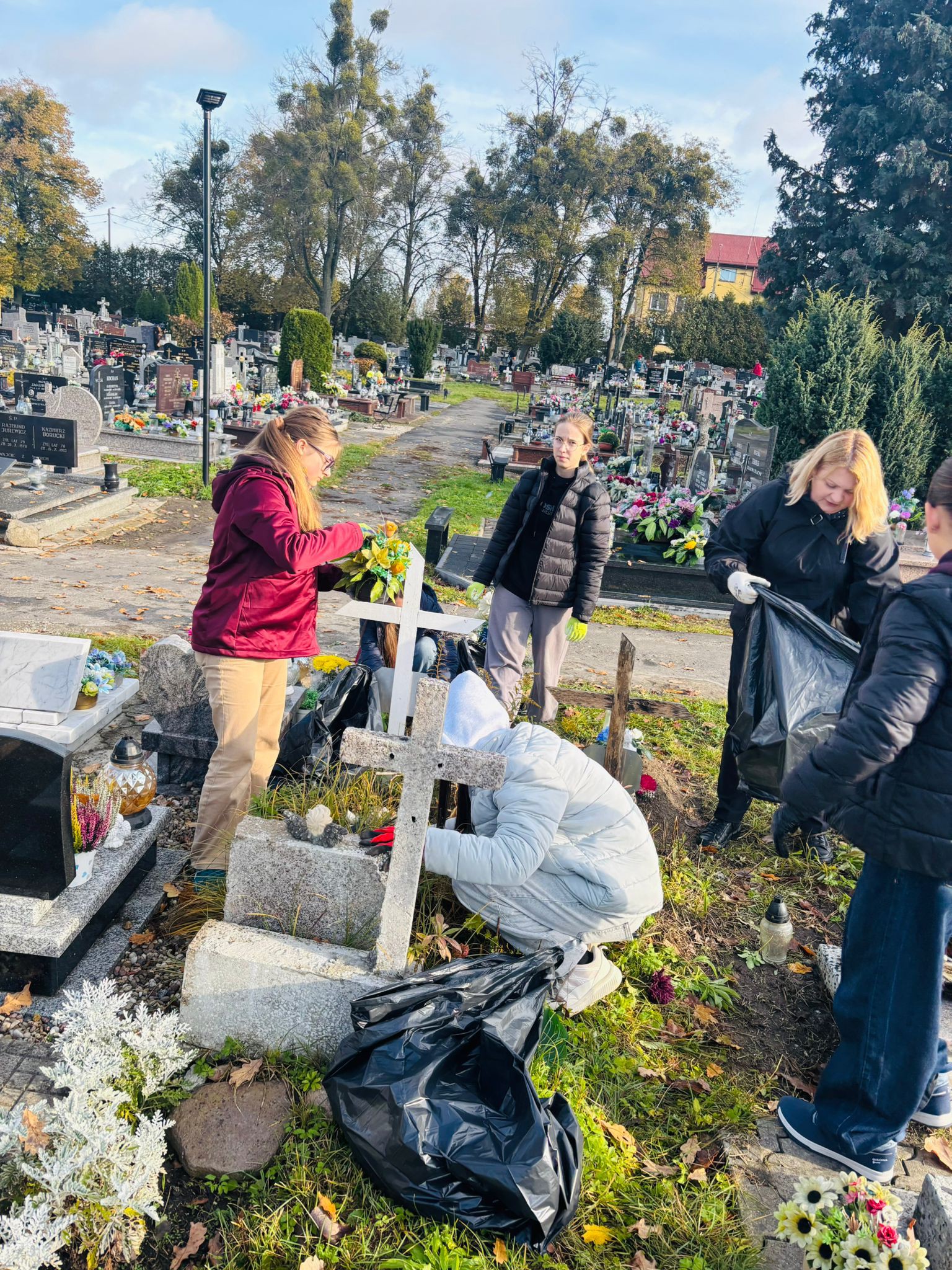 Wolontariusze sprzątają groby na cmentarzu komunalnym w Szczytnie