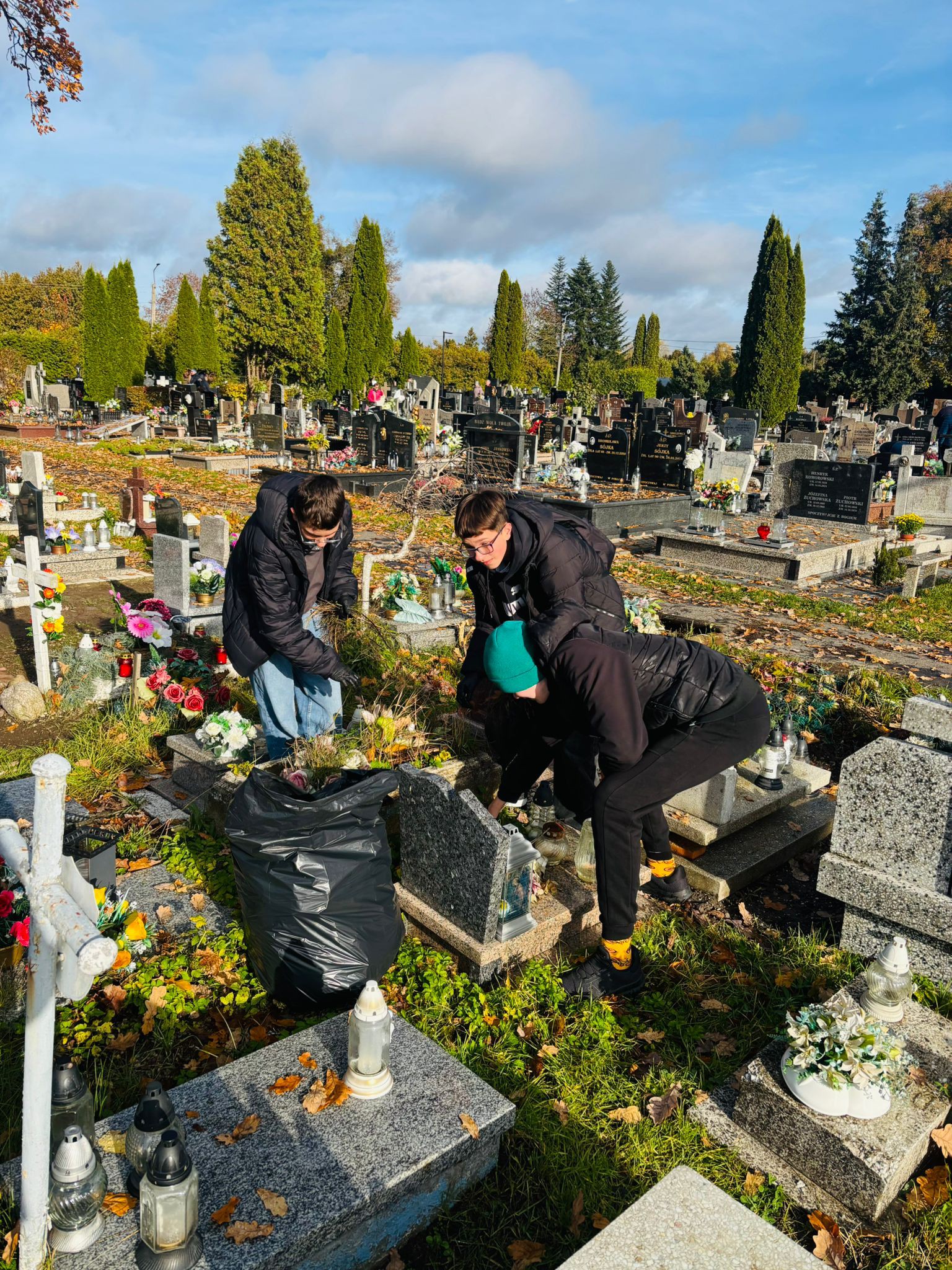 Wolontariusze sprzątają groby na cmentarzu komunalnym w Szczytnie