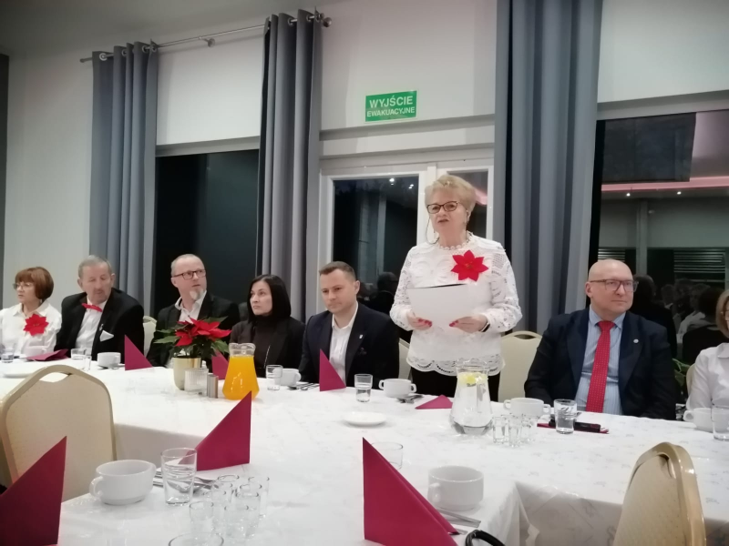 osoby siedzące przy stole, jedna kobieta stoi i przemawia