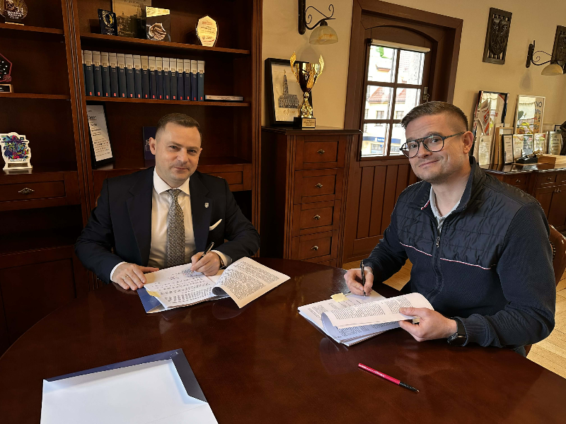 dwie osoby, przy stole podpisywanie umowy